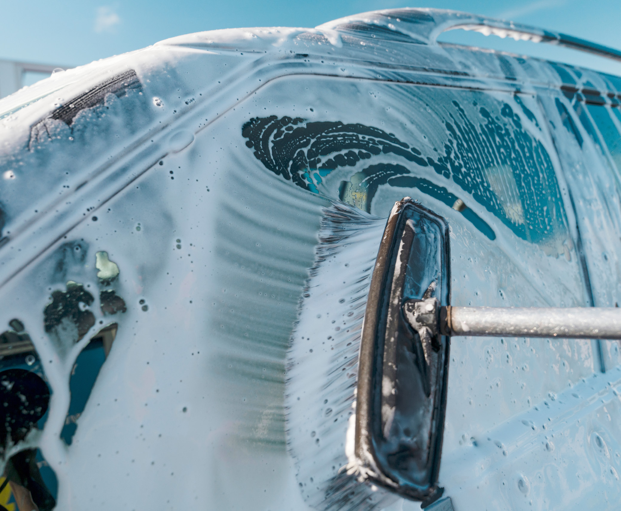 A car being professionally washed with soap suds at We Shine Any Car